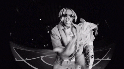 A Man Wearing Sunglasses Is Dancing On A Basketball Court . GIF