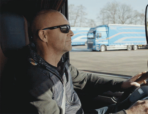 a man wearing sunglasses is driving a car