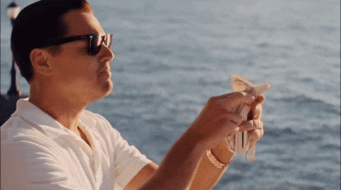 A Man Wearing Sunglasses Is Holding A Bunch Of Money In His Hands GIF
