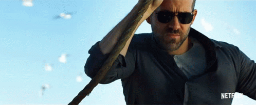 A Man Wearing Sunglasses Is Holding A Cane In Front Of A Blue Sky GIF