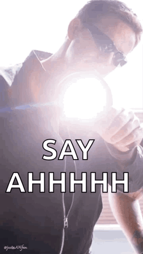 A Man Wearing Sunglasses Is Holding A Light Bulb In His Hand And Says Say Ahhhh GIF