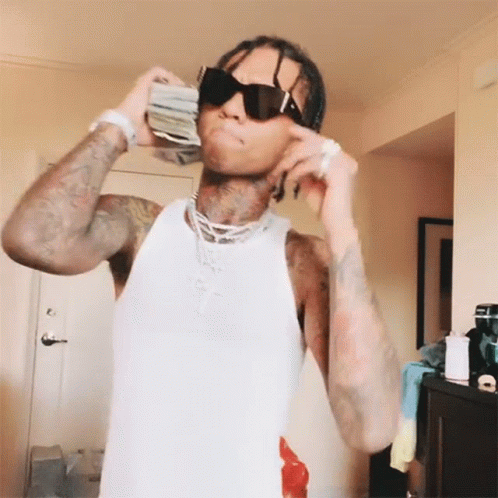 A Man Wearing Sunglasses Is Holding A Stack Of Money In His Hand GIF