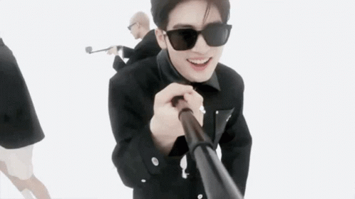 A Man Wearing Sunglasses Is Holding A Stick In His Hand While Standing Next To Another Man . GIF