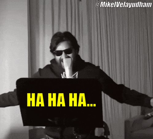 A Man Wearing Sunglasses Is Laughing In Front Of A Laptop Screen That Says Ha Ha Ha GIF