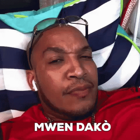 A Man Wearing Sunglasses Is Laying On A Striped Pillow . GIF