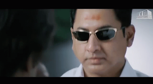 A Man Wearing Sunglasses Is Looking At Another Man 'S Face GIF