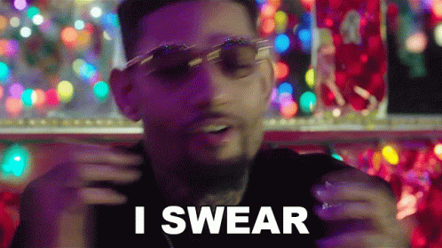a man wearing sunglasses is saying i swear in front of christmas lights
