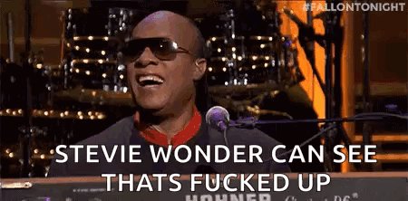 A Man Wearing Sunglasses Is Singing Into A Microphone While Playing A Keyboard . GIF