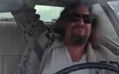 A Man Wearing Sunglasses Is Sitting In A Car With His Arms Outstretched . GIF