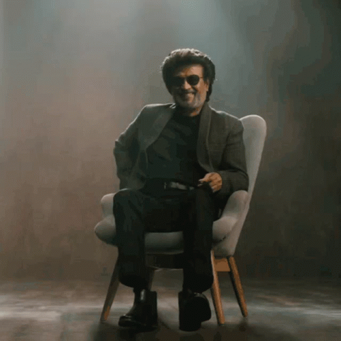 A Man Wearing Sunglasses Is Sitting In A Chair And Smiling GIF
