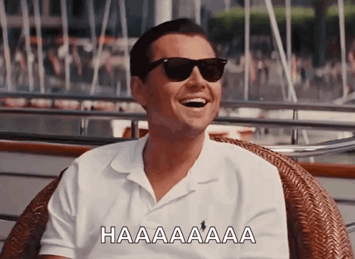 A Man Wearing Sunglasses Is Sitting In A Wicker Chair And Laughing GIF