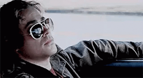 A Man Wearing Sunglasses Is Sitting In The Back Seat Of A Car . GIF
