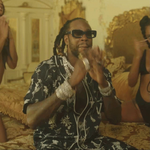 A Man Wearing Sunglasses Is Sitting On A Bed Next To Two Women In Bikinis GIF