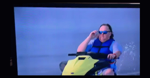 A Man Wearing Sunglasses Is Sitting On A Jet Ski GIF