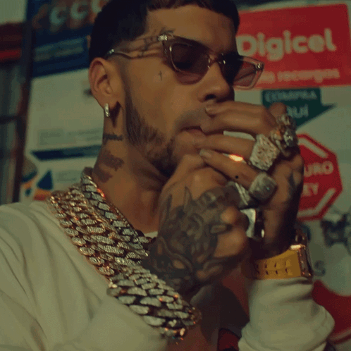 A Man Wearing Sunglasses Is Smoking A Cigar In Front Of A Sign That Says Digical GIF