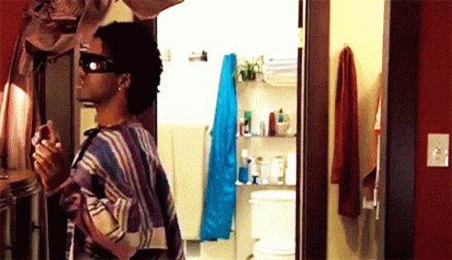 a man wearing sunglasses is standing in a bathroom