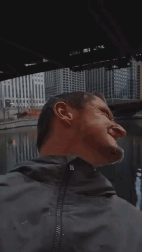 A Man Wearing Sunglasses Is Standing In Front Of A City Skyline . GIF