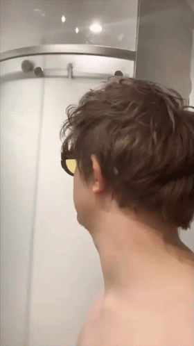 A Man Wearing Sunglasses Is Standing In Front Of A Shower GIF