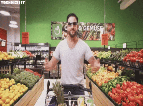 A Man Wearing Sunglasses Is Standing In Front Of A Sign That Says " C & Gemuse " GIF