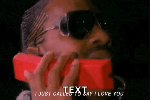 A Man Wearing Sunglasses Is Talking On A Red Phone And Says I Just Called To Say I Love You . GIF