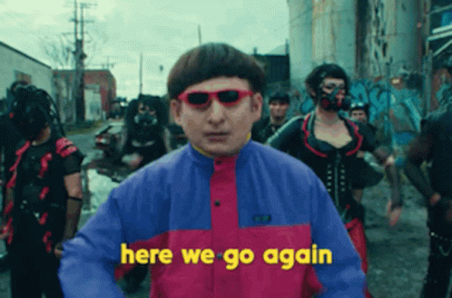 A Man Wearing Sunglasses Says Here We Go Again In Front Of A Crowd Of People GIF