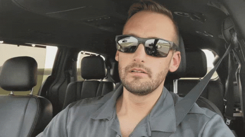 a man wearing sunglasses sits in a car