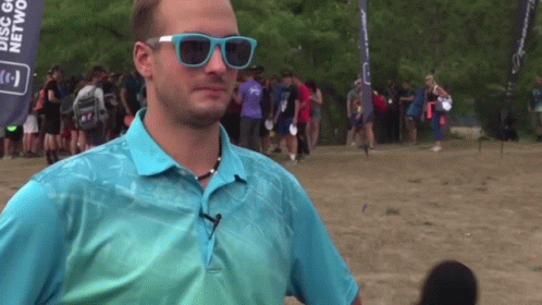 a man wearing sunglasses stands in front of a banner that says disc golf