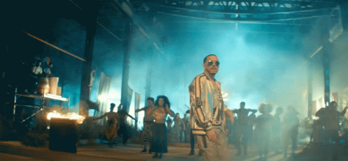 A Man Wearing Sunglasses Stands In Front Of A Crowd GIF