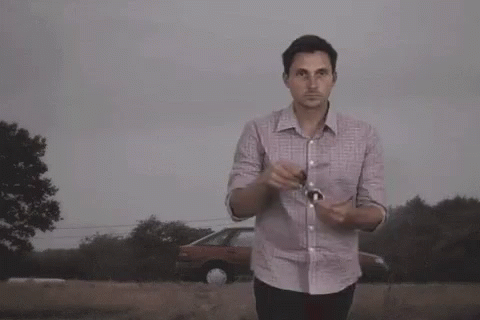 A Man Wearing Sunglasses Stands In Front Of A Large Explosion GIF