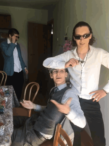A Man Wearing Sunglasses Stands Next To Another Man GIF