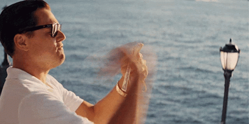 A Man Wearing Sunglasses Takes A Picture Of The Water GIF