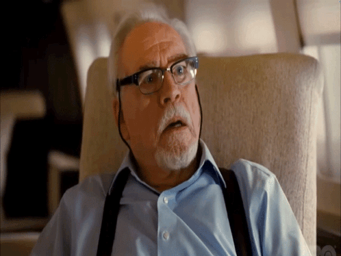 A Man Wearing Suspenders And Glasses Looks Surprised GIF