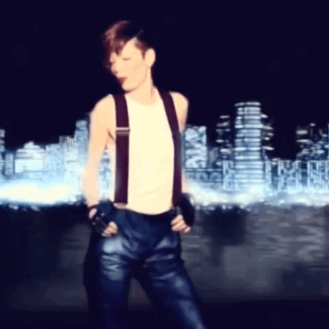 A Man Wearing Suspenders And Gloves Is Dancing In Front Of A City Skyline GIF