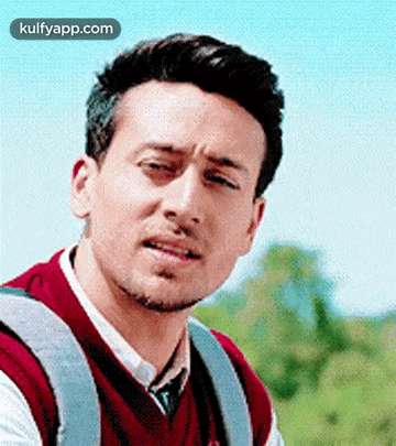 A Man With A Backpack Is Making A Funny Face While Looking At The Camera . GIF
