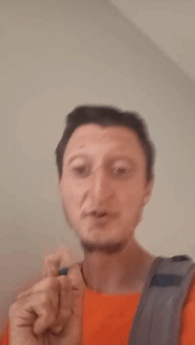 A Man With A Backpack Is Making A Shhh Gesture With His Finger To His Mouth . GIF