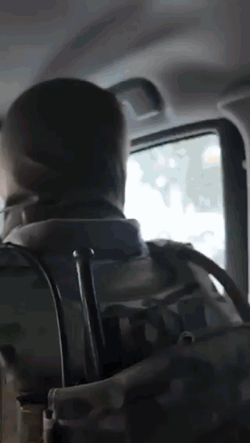 A Man With A Backpack Is Sitting In The Back Seat Of A Car Looking Out The Window GIF