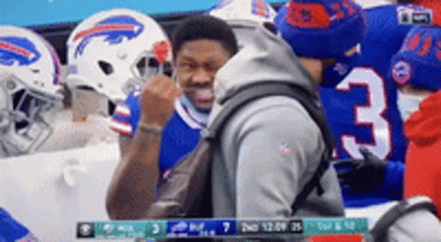 A Man With A Backpack Is Standing In Front Of A Group Of Buffalo Bills Football Players . GIF