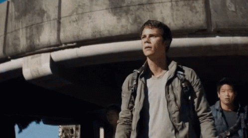 A Man With A Backpack Stands In Front Of A Concrete Building GIF