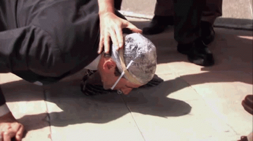 A Man With A Bandage On His Head Is Kneeling Down On The Ground GIF