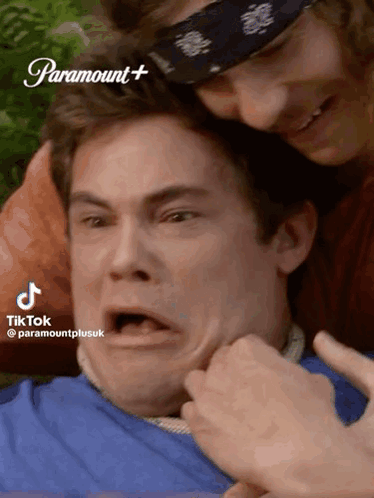 A Man With A Bandana On His Head Is Being Held By Another Man .. GIF