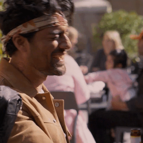 A Man With A Bandana On His Head Is Laughing At Something GIF
