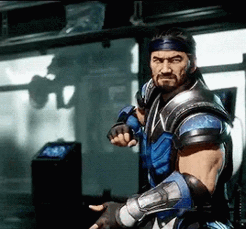 A Man With A Beard And A Bandana On His Head Is Standing In A Room Holding A Sword . GIF