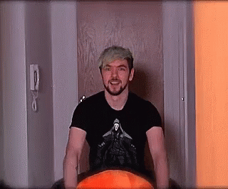 A Man With A Beard And A Black Shirt Is Standing In A Doorway . GIF