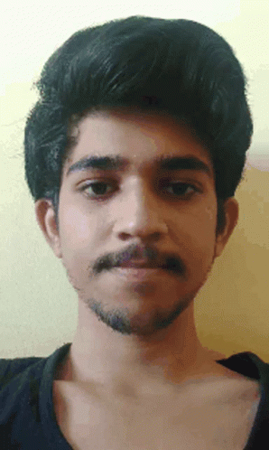 A Man With A Beard And A Black Shirt Looks At The Camera GIF