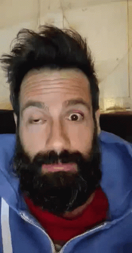 A Man With A Beard And A Blue Jacket Is Making A Funny Face GIF