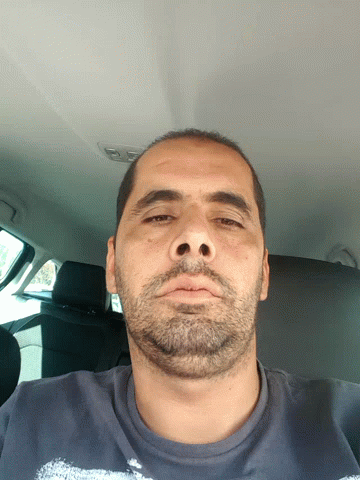 A Man With A Beard And A Blue Shirt Is Looking Down GIF