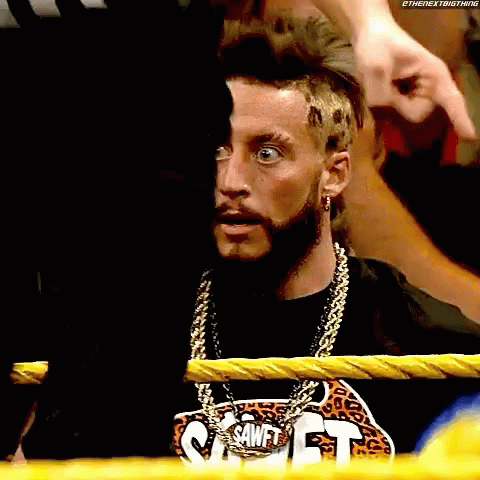 a man with a beard and a chain around his neck is sitting in a boxing ring .