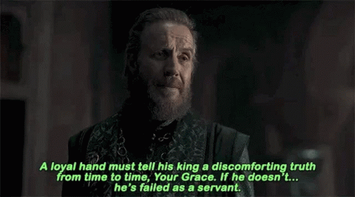 a man with a beard and a chain around his neck is talking to another man .