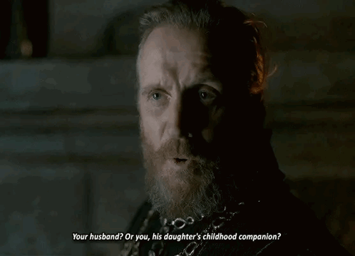 a man with a beard and a chain around his neck is talking to another man .