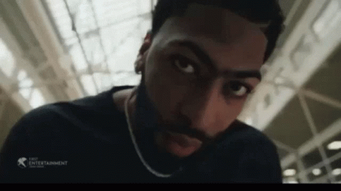 A Man With A Beard And A Chain Around His Neck Looks At The Camera GIF